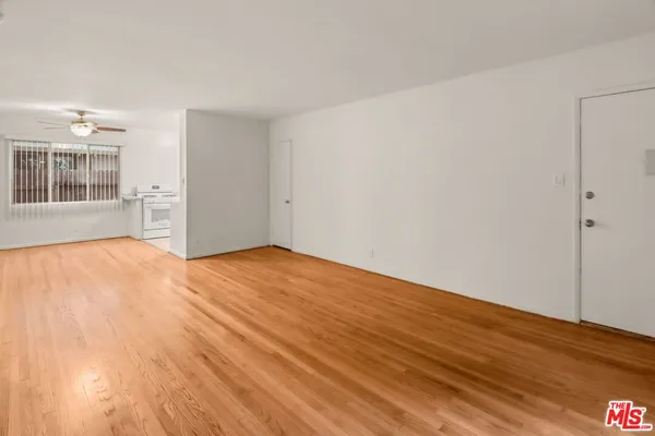 a view of empty room with wooden floor and fan