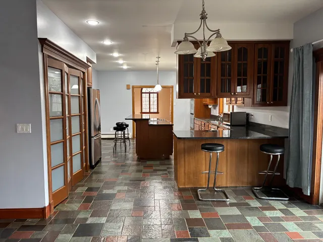 a view of dining room with granite countertop kitchen island stainless steel appliances a sink a counter top space and a window