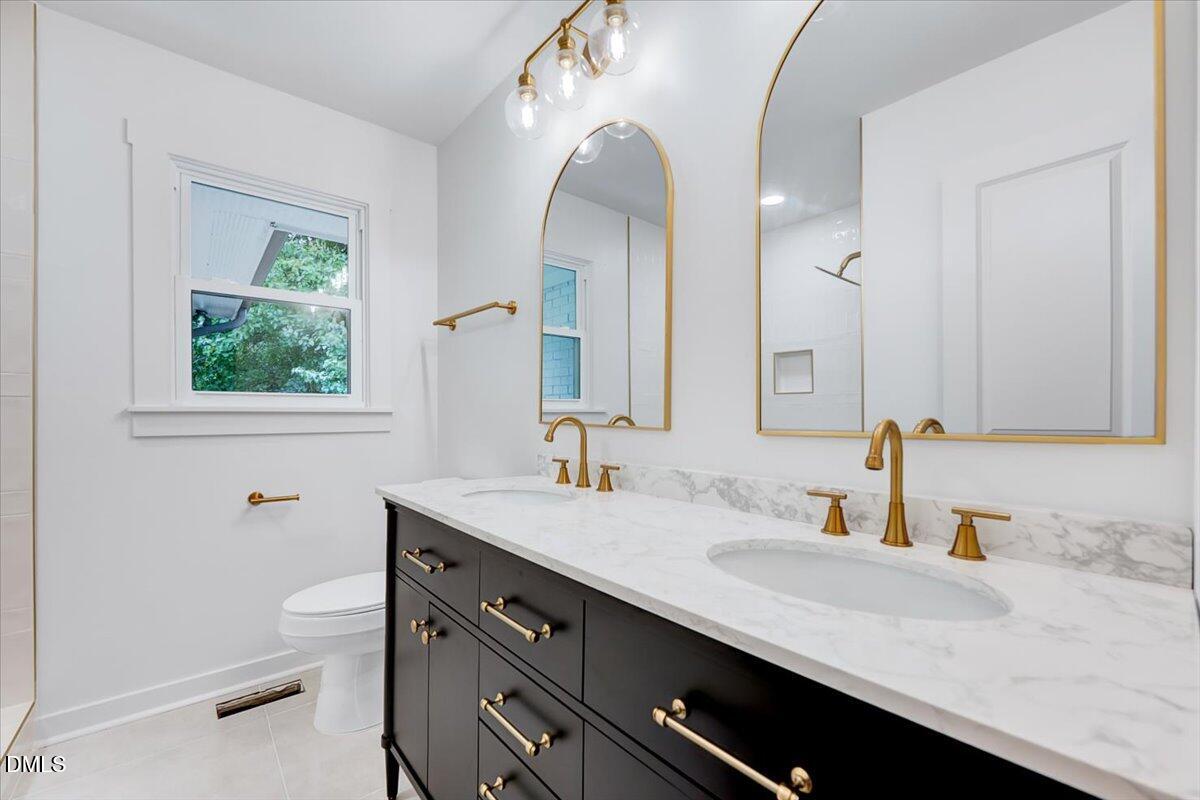 601 West Walnut Street Selma, NC 27576 - Photo 19 of 30 a bathroom with a granite countertop sink a toilet and a mirror
