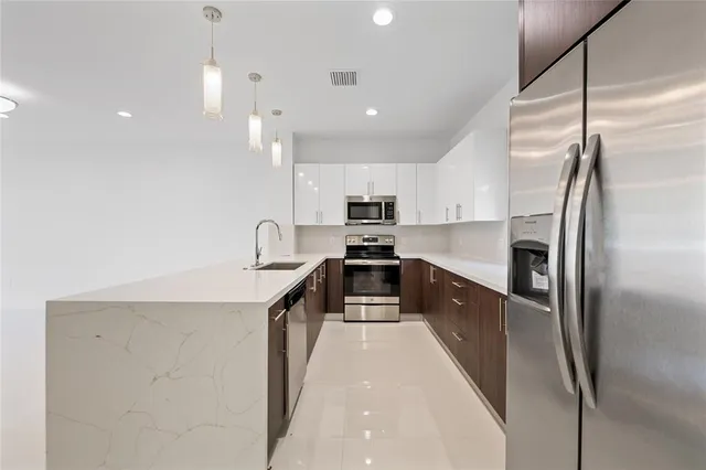 a kitchen with stainless steel appliances granite countertop a refrigerator a sink a stove and a sink with wooden floor