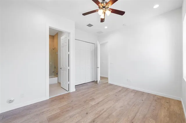 an empty room with wooden floor and fan