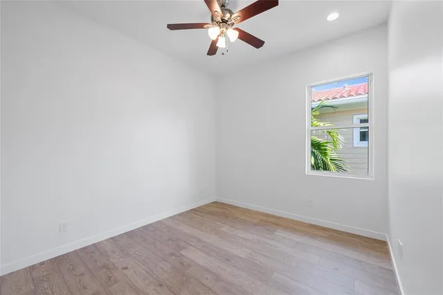 an empty room with a window and a ceiling fan