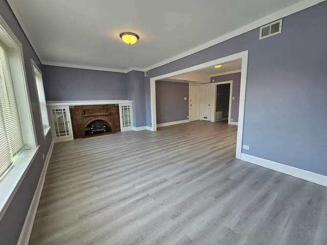 a view of empty room with wooden floor and fireplace