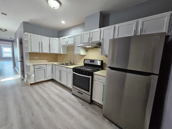 a kitchen with a refrigerator a stove top oven a sink and cabinets