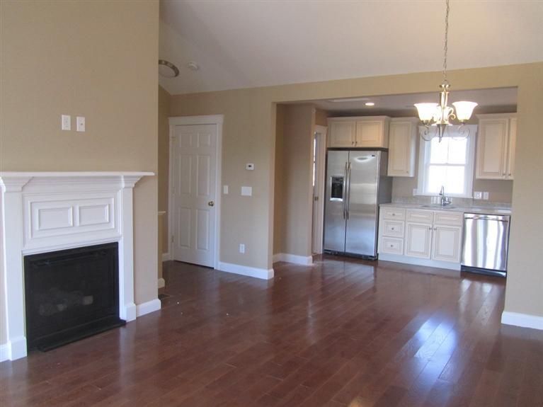 161 Route 28, Unit 7 West Harwich, MA 02671 - Photo 6 of 16 an empty room with wooden floor fireplace and kitchen view