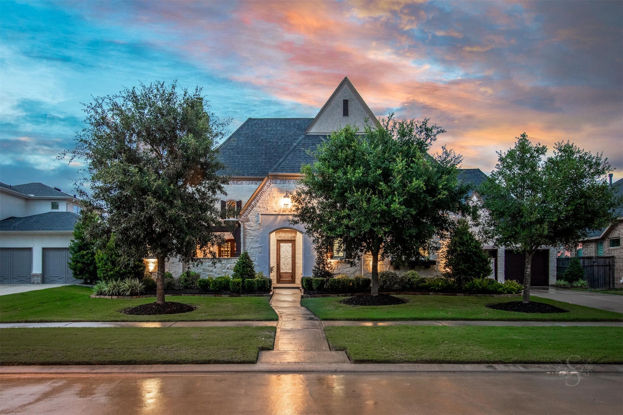 28602 Hoffman Spring Lane Fulshear, TX 77441 - Photo 5 of 50 Spectacular 2 story Huntington home set on an expansive greenbelt lot, offering 5,513 square feet, 5 bedrooms (2 down), 5 full and 3 half baths, and a rare 4-car garage. From the moment you arrive, the timeless stone façade, manicured landscape, and private courtyard entry create a striking first impression of the scale and architectural presence found throughout.