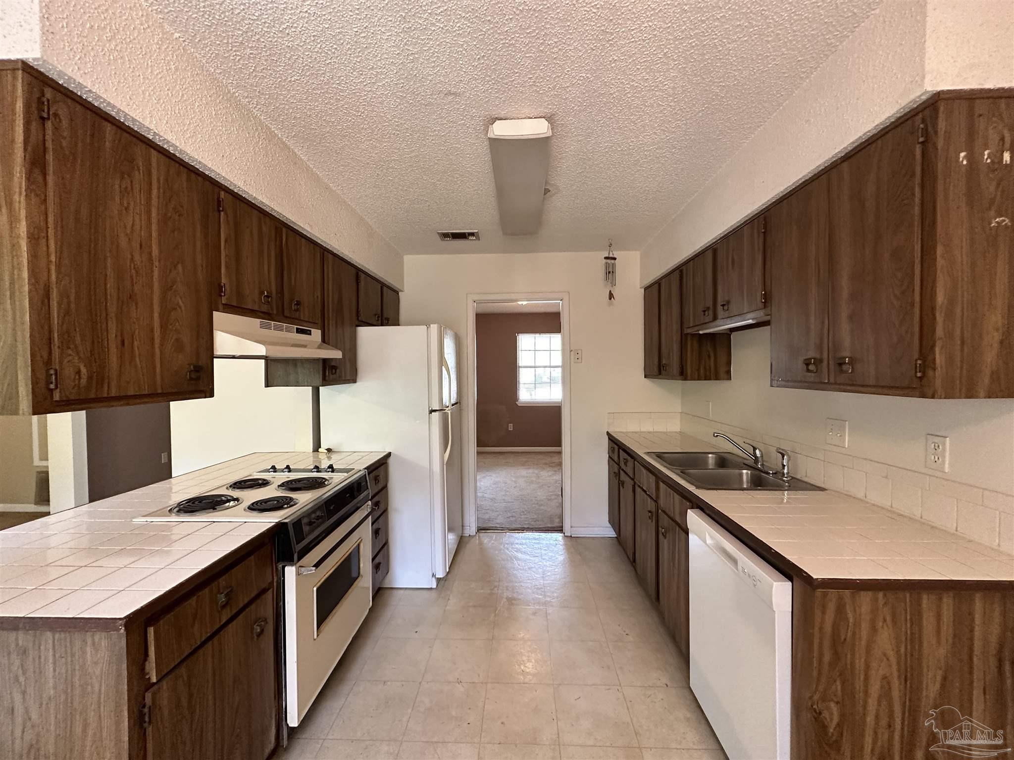 511 Maple Avenue Niceville, FL 32578 - Photo 4 of 17 a kitchen with stainless steel appliances a sink dishwasher stove refrigerator and cabinets