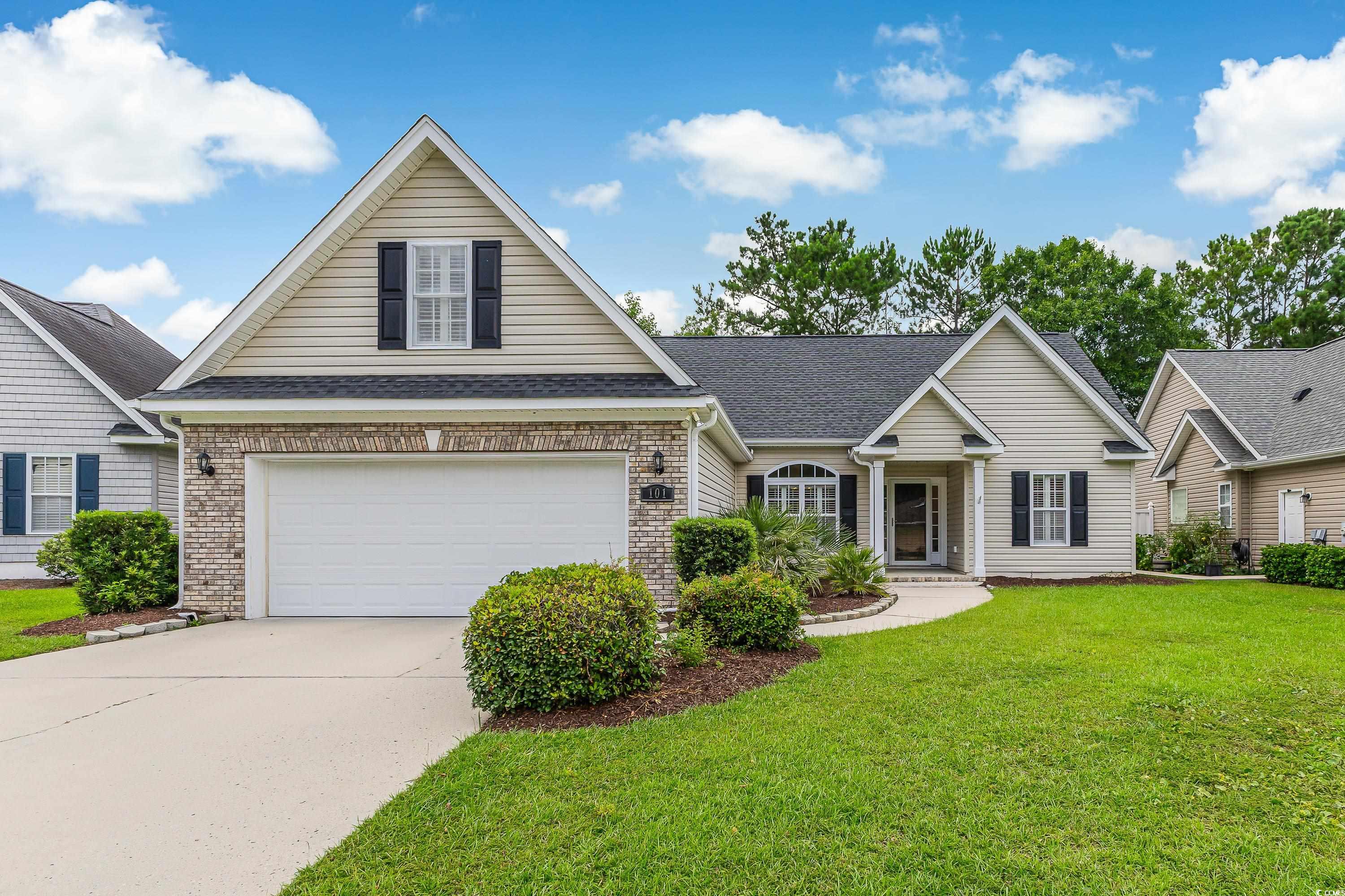 Traditional-style home featuring brick siding, roof with shingles, concrete driveway, and a front lawn