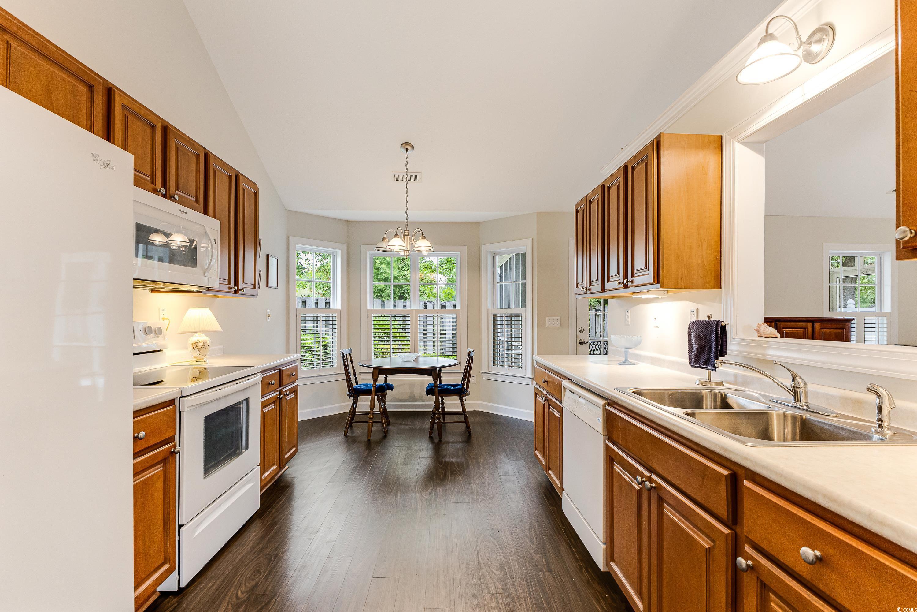 101 Cedar Tree Lane Southwest Calabash, NC 28467 - Photo 14 of 40 Kitchen with white appliances, light countertops, dark wood-style floors, vaulted ceiling, and decorative light fixtures
