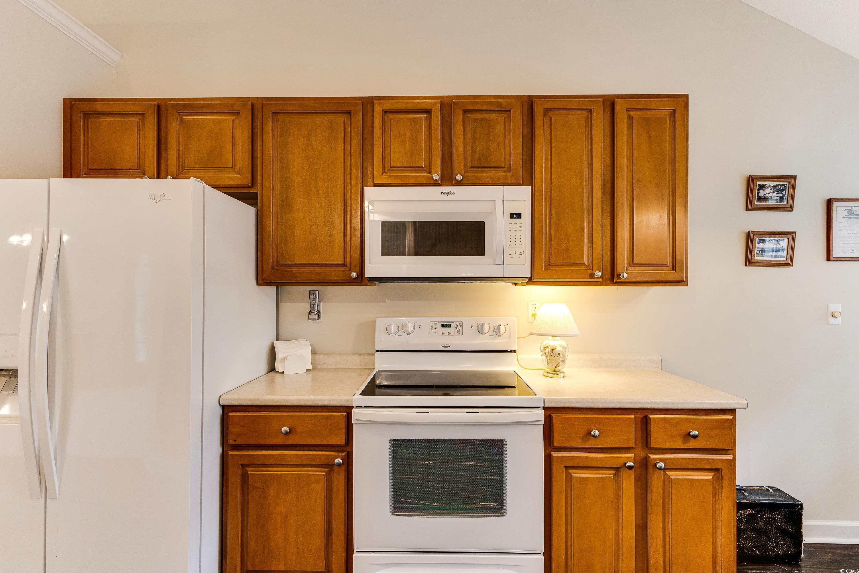 101 Cedar Tree Lane Southwest Calabash, NC 28467 - Photo 17 of 40 Kitchen with white appliances, light countertops, brown cabinets, and ornamental molding