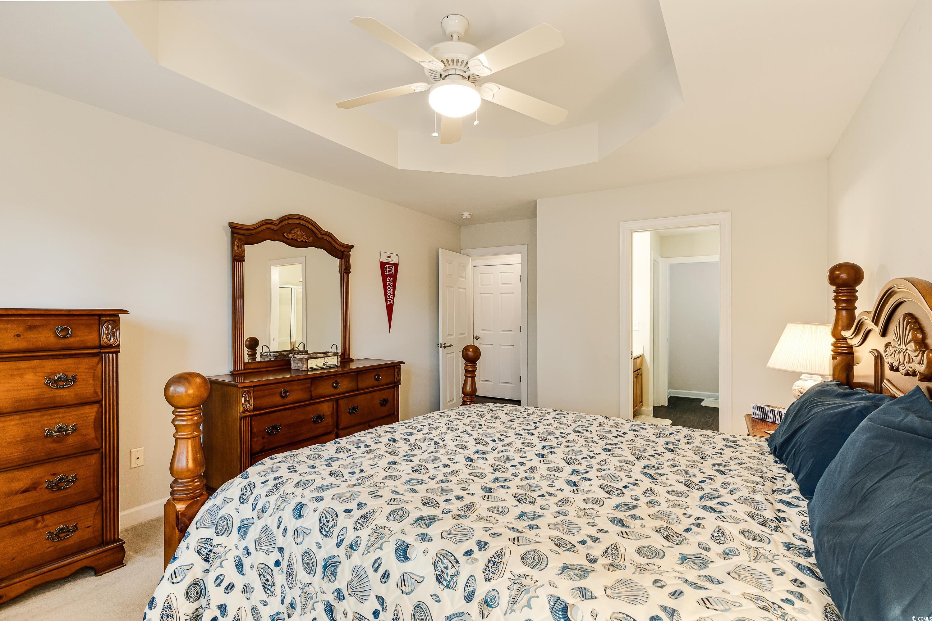 101 Cedar Tree Lane Southwest Calabash, NC 28467 - Photo 20 of 40 Bedroom with a raised ceiling, light colored carpet, and ceiling fan