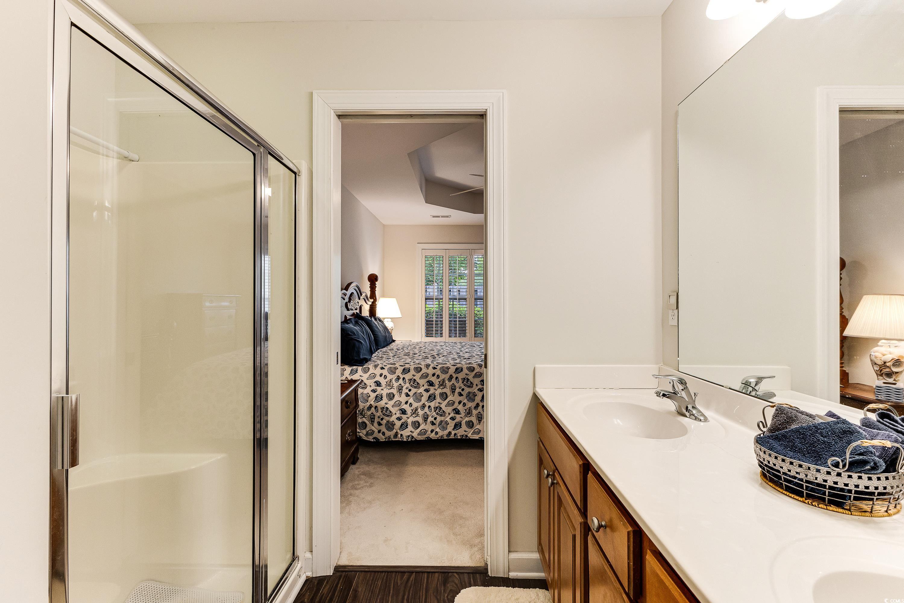 101 Cedar Tree Lane Southwest Calabash, NC 28467 - Photo 22 of 40 Ensuite bathroom featuring a stall shower, double vanity, and wood finished floors