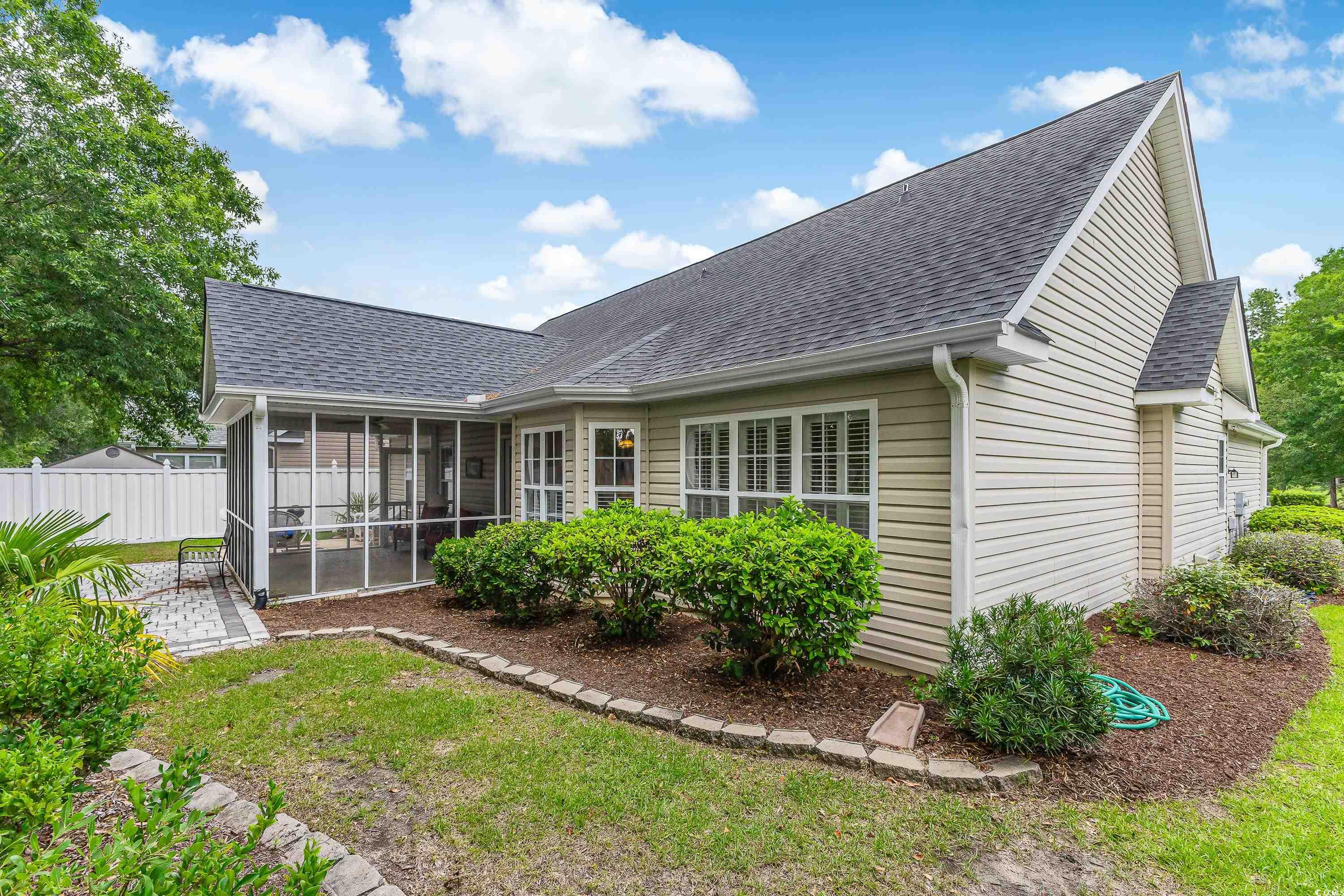 101 Cedar Tree Lane Southwest Calabash, NC 28467 - Photo 33 of 40 Rear view of house featuring a sunroom, a shingled roof, and a patio area