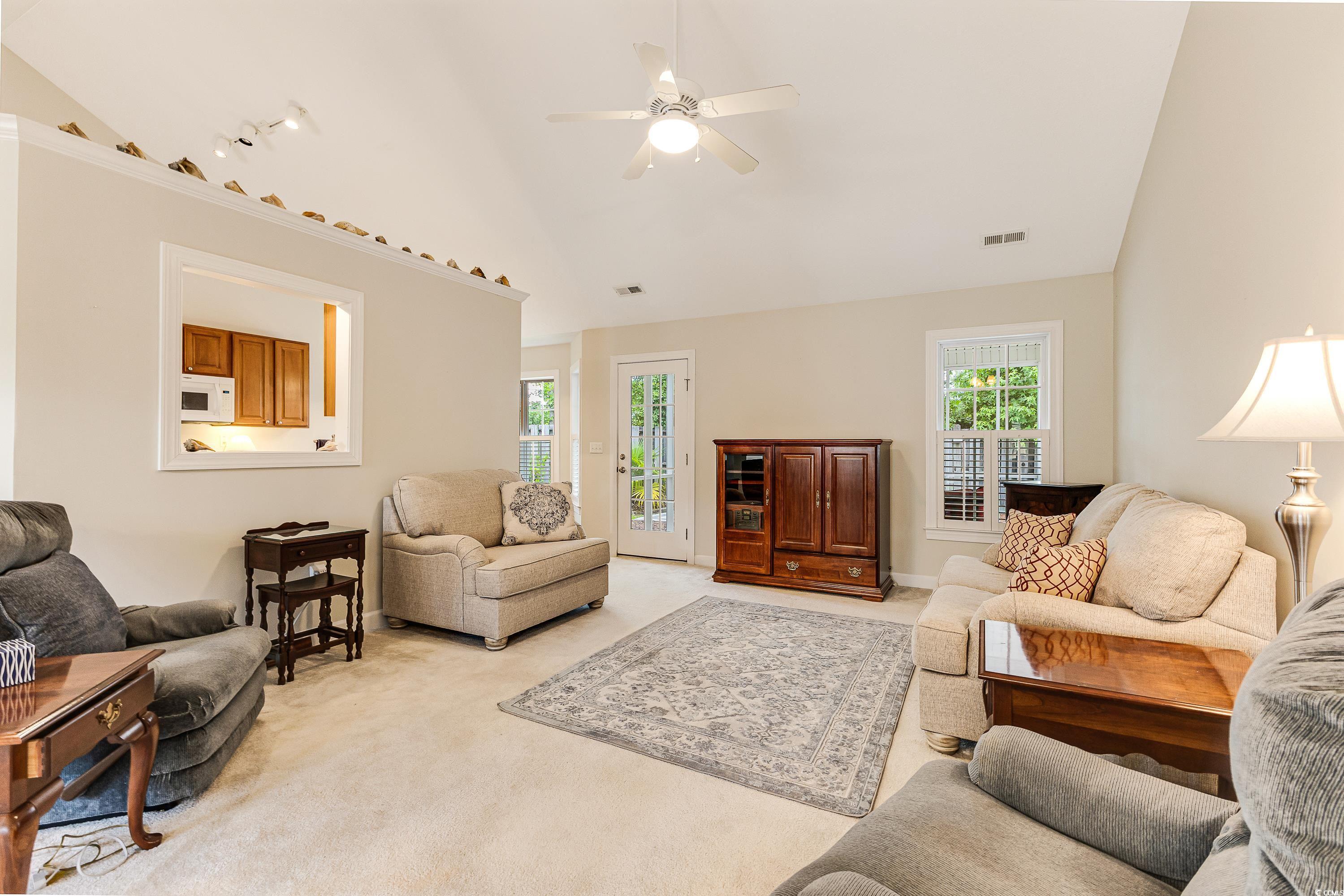 101 Cedar Tree Lane Southwest Calabash, NC 28467 - Photo 6 of 40 Living area with vaulted ceiling, plenty of natural light, light carpet, and a ceiling fan