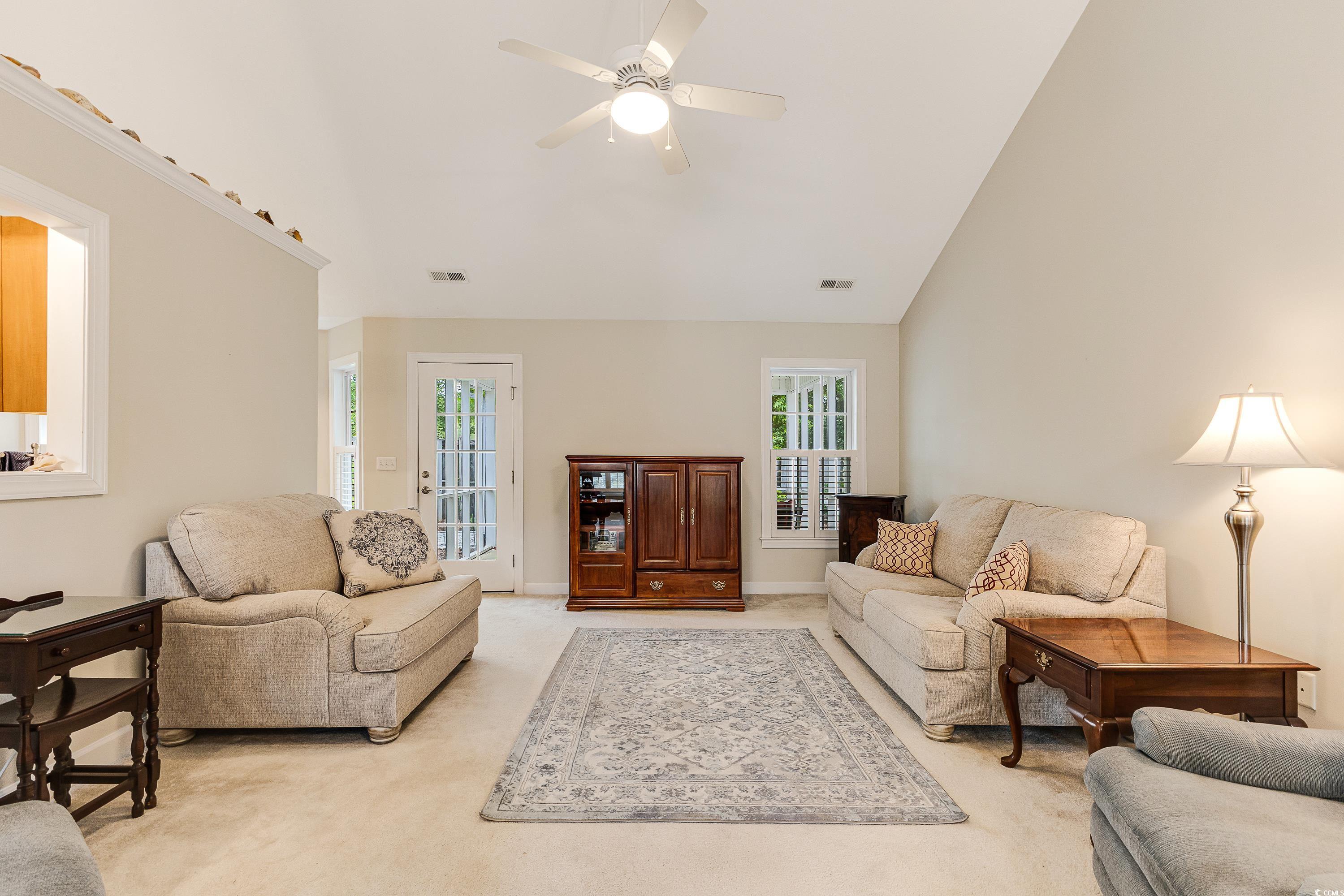 101 Cedar Tree Lane Southwest Calabash, NC 28467 - Photo 7 of 40 Living area with light carpet, high vaulted ceiling, and ceiling fan