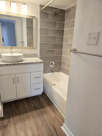 a bathroom with a granite countertop sink and a bathtub