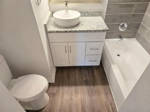 a bathroom with a granite countertop sink toilet and a mirror