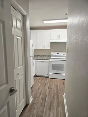 a kitchen with a hard wood floor white cabinets and stainless steel appliances