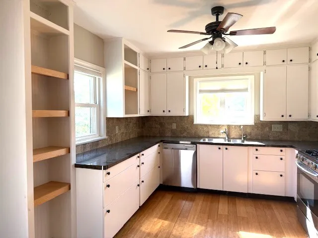 a kitchen with granite countertop a sink a window stainless steel appliances and cabinets