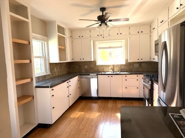 a kitchen with granite countertop a refrigerator a sink and dishwasher with wooden floor
