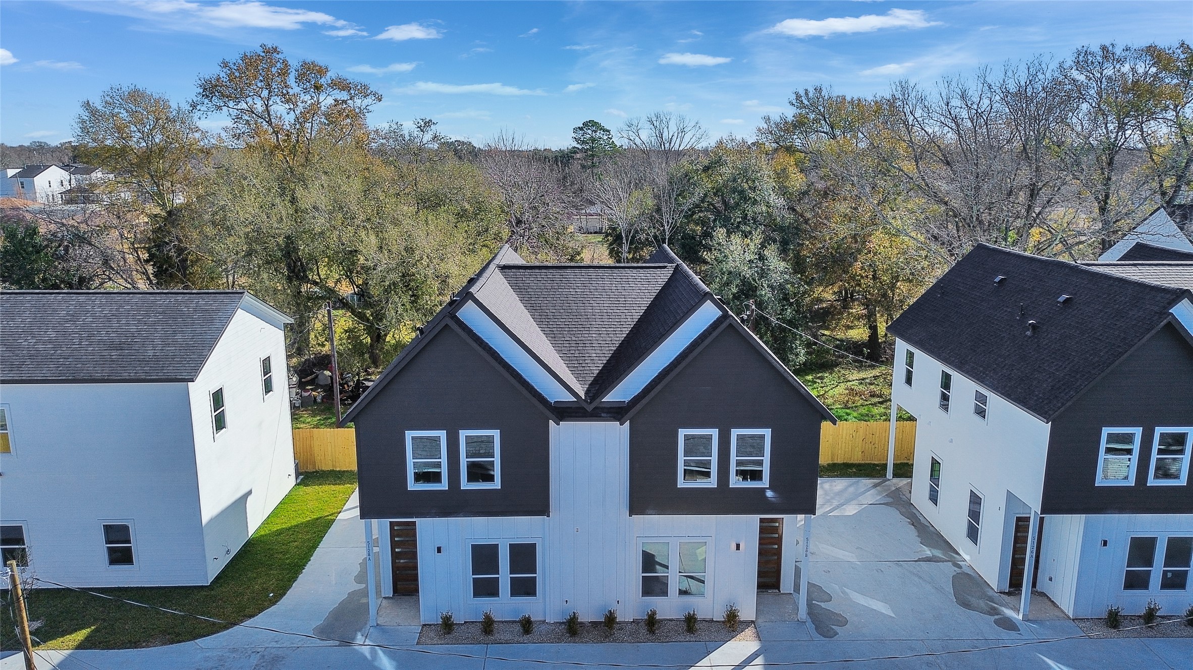 5126 Clover Street, Unit A/B Houston, TX 77033 - Photo 1 of 29 This photo shows a modern, two-story home with a dark roof and contrasting light siding. It features a neat driveway and is situated in a residential area with trees in the background, offering a blend of suburban and natural surroundings.