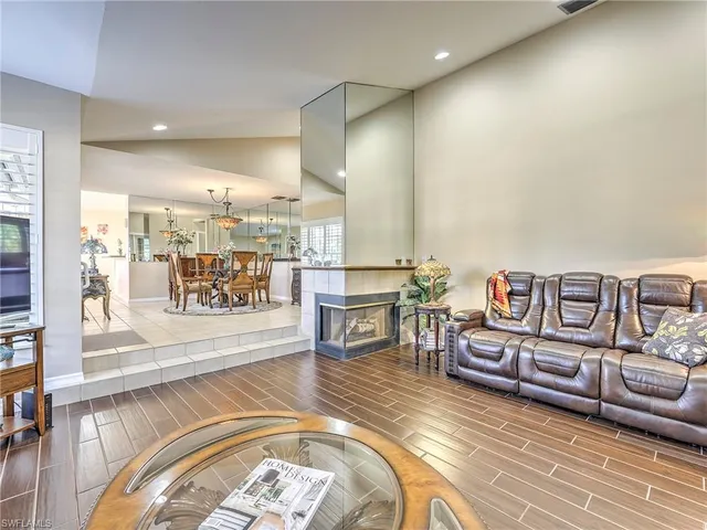 a living room with couches and kitchen view with wooden floor