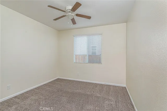 an empty room with a window and a fan