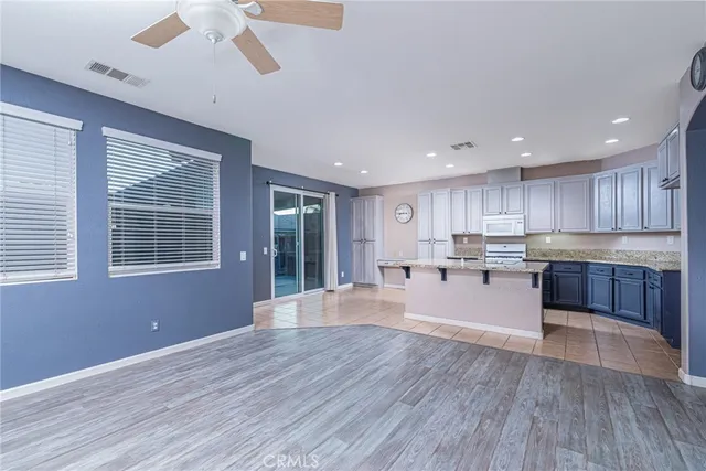 a large kitchen with stainless steel appliances granite countertop a large counter top a wooden floors and a fireplace