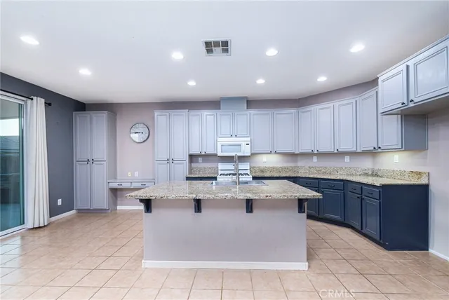 a large kitchen with stainless steel appliances granite countertop a sink dishwasher a stove and a refrigerator with wooden cabinets