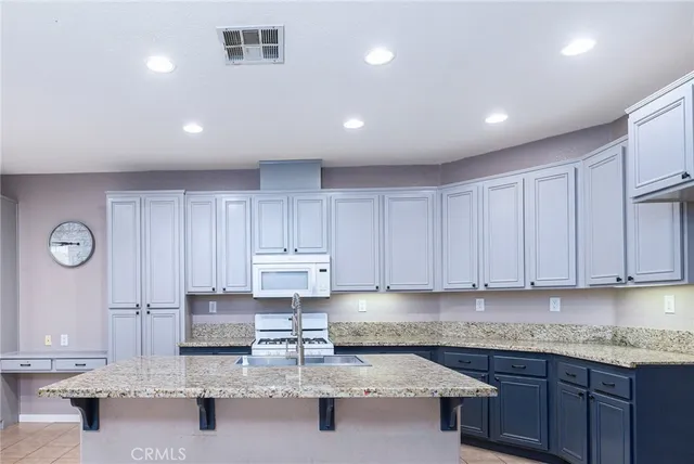 a kitchen with granite countertop a sink a stove and cabinets