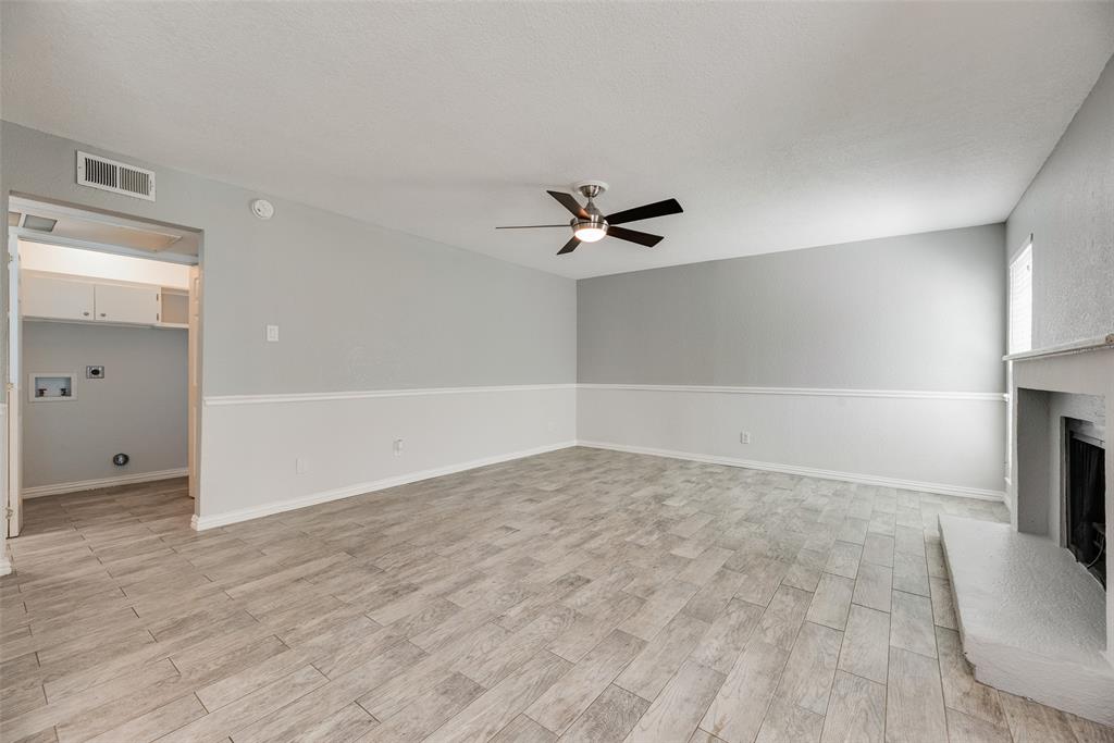 5109 Cedar Springs Road, Unit 105 Dallas, TX 75235 - Photo 5 of 16 Spacious living area featuring wood-finish flooring, a ceiling fan, and a built-in fireplace