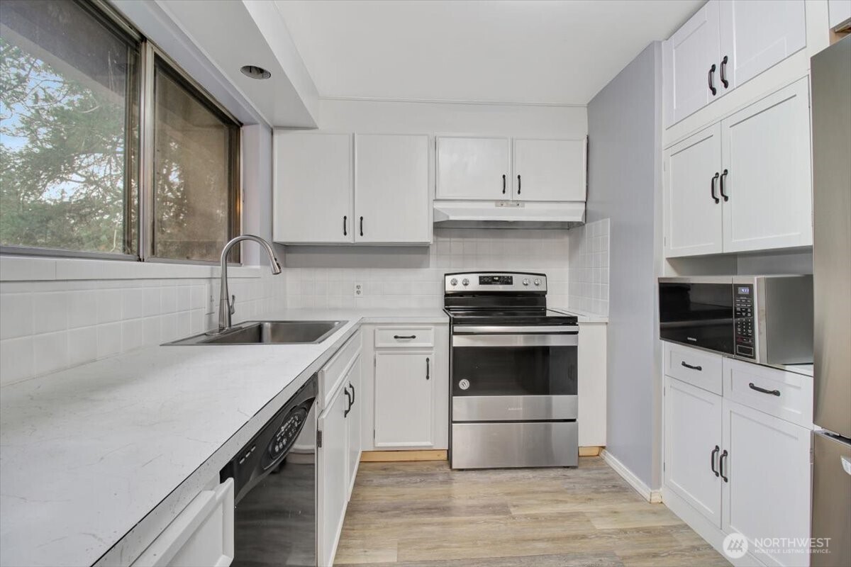 7313 228th Street Southwest Mountlake Terrace, WA 98043 - Photo 9 of 34 a kitchen with granite countertop a sink a stove and cabinets