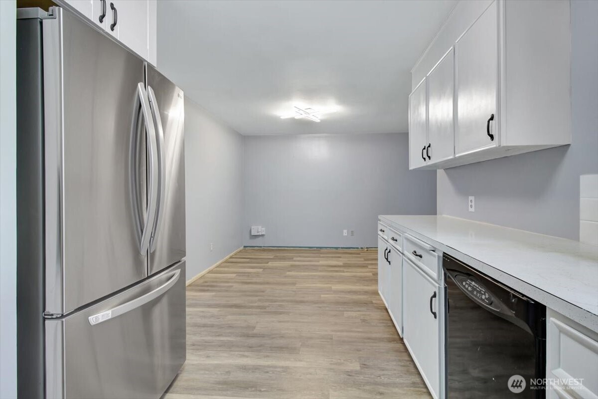 7313 228th Street Southwest Mountlake Terrace, WA 98043 - Photo 10 of 34 a kitchen with granite countertop stainless steel appliances and wooden floor