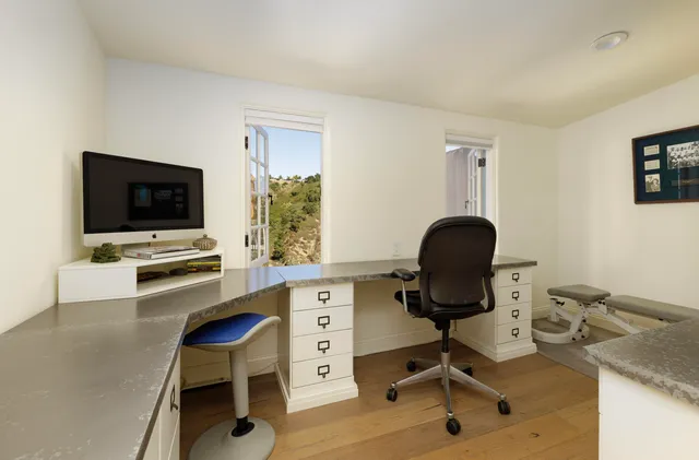 a view of a workspace with furniture and a window