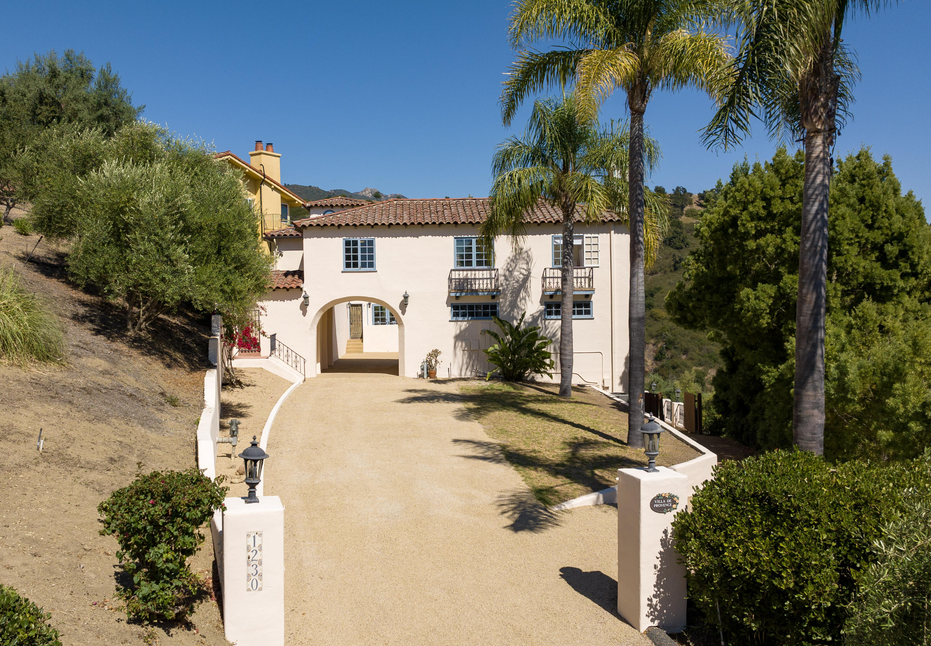 1230 Northridge Road Santa Barbara, CA 93105 - Photo 3 of 36 a view of a white house with a yard and potted plants