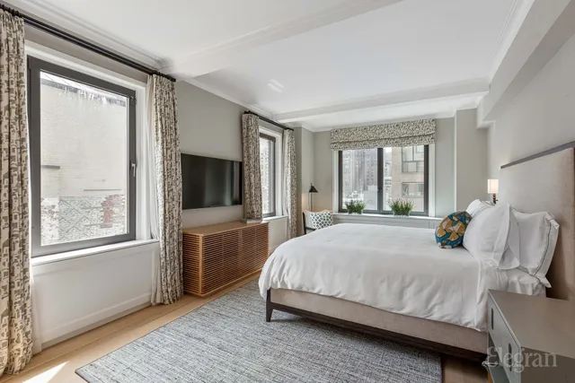 a bedroom with a large bed and a flat tv screen