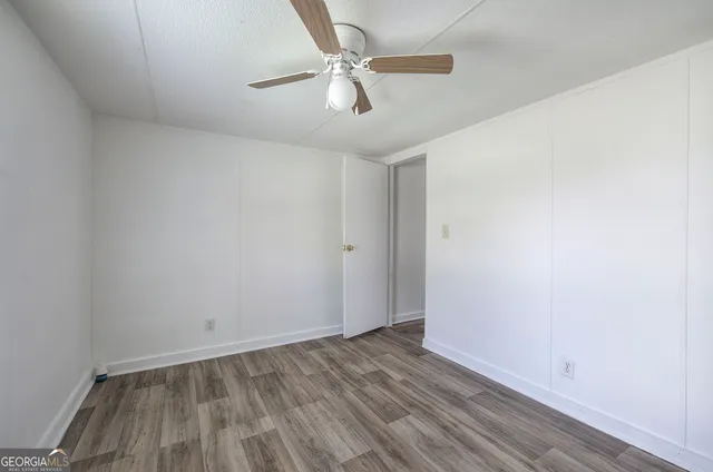 an empty room with wooden floor and ceiling fan