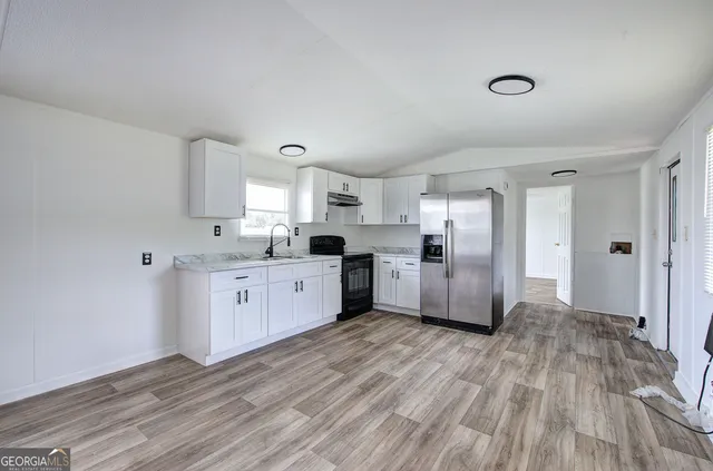 a large kitchen with a wooden floor and stainless steel appliances