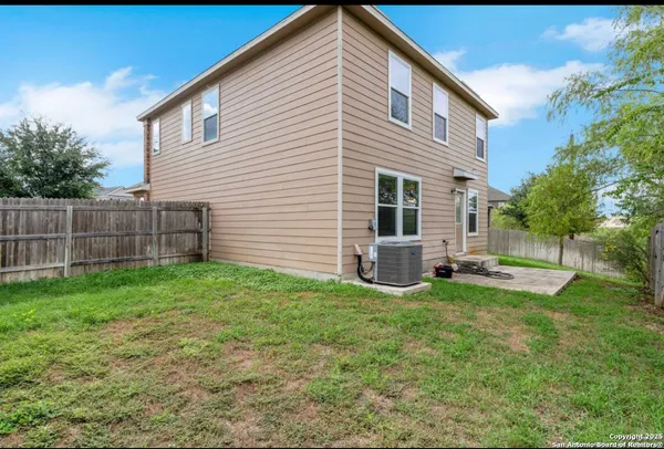 a backyard of a house with plants and wooden fence