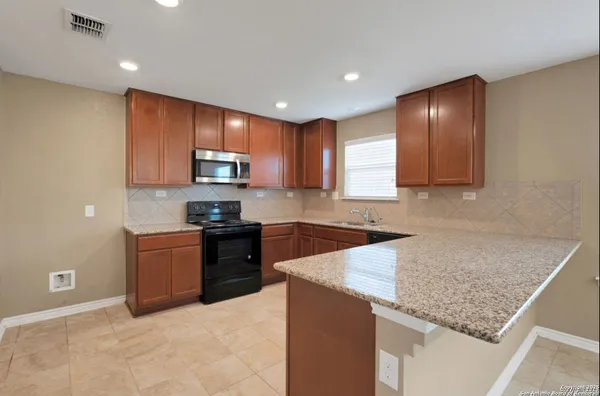 a kitchen with granite countertop wooden cabinets and stainless steel appliances