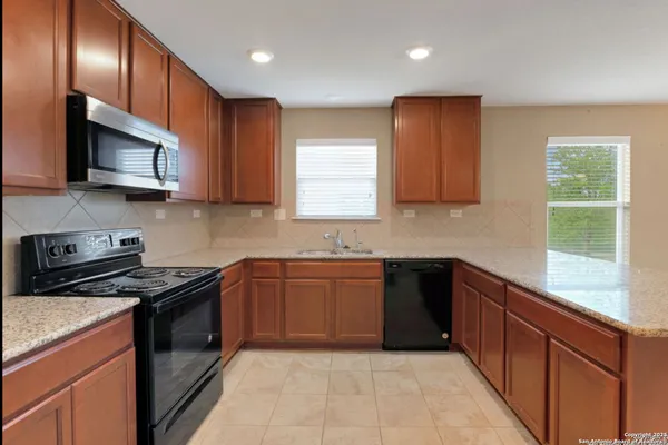 a kitchen with stainless steel appliances granite countertop wooden cabinets a stove top oven a sink and dishwasher