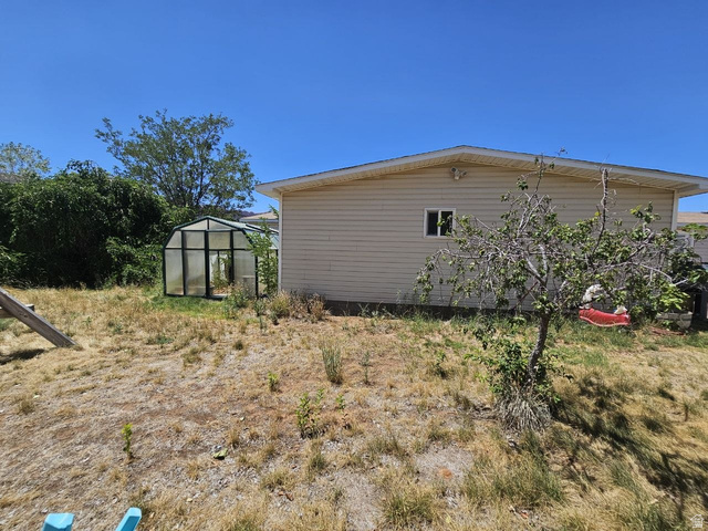 52 Quail Court Moab, UT 84532 - Photo 26 of 36 Rear exterior featuring horizontal siding, a framed window, and a greenhouse structure