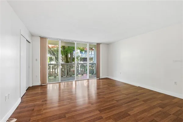 a view of an empty room with wooden floor and a window
