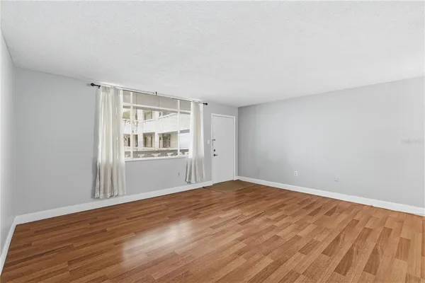 a view of an empty room with a window and wooden floor