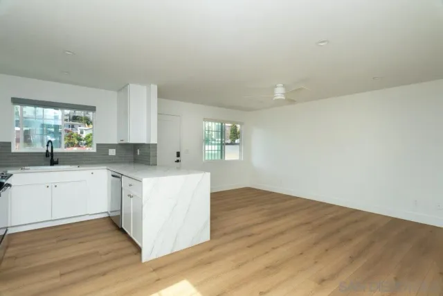 a kitchen with granite countertop white cabinets and wooden floor