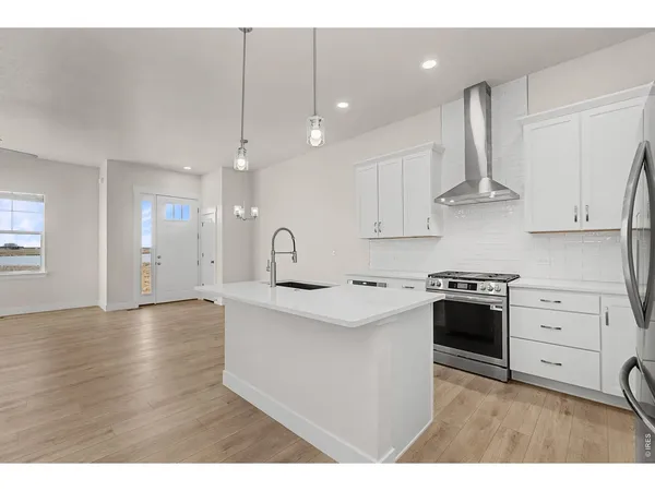 a kitchen with stainless steel appliances granite countertop a sink a stove a refrigerator and white cabinets
