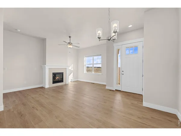 a view of an empty room with a fireplace and wooden floor