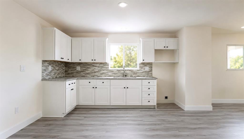 7061 Base Street Azle, TX 76020 - Photo 8 of 13 Contemporary kitchen featuring white cabinetry, a mosaic tile backsplash, speckled countertops, and wood-finish flooring