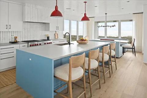 a kitchen with a dining table chairs sink and white cabinets