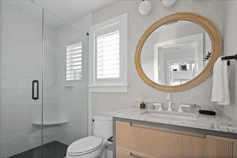 a bathroom with a granite countertop toilet a sink and a mirror